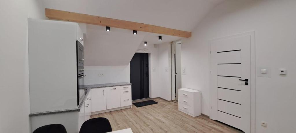 una cucina bianca con armadi bianchi e pavimenti in legno di Apartament przy Małej Panwi "II" a Opole