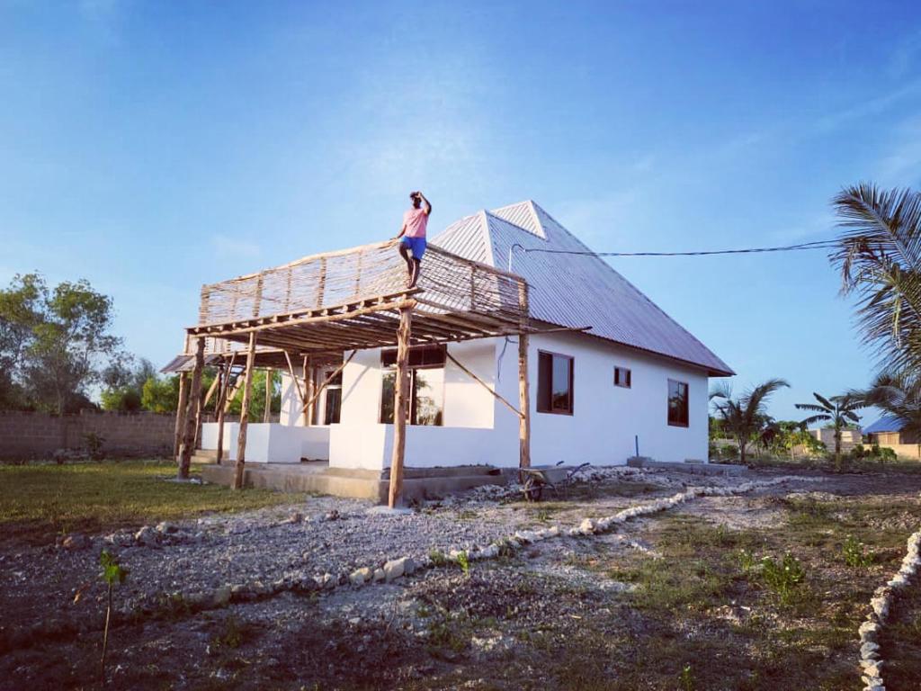 un hombre parado en el techo de una casa en Villa Pumziko, en Kizimkazi