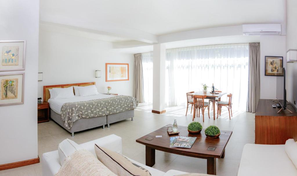 a bedroom with a bed and a living room with a table at Hotel Boutique Raíces in Curicó