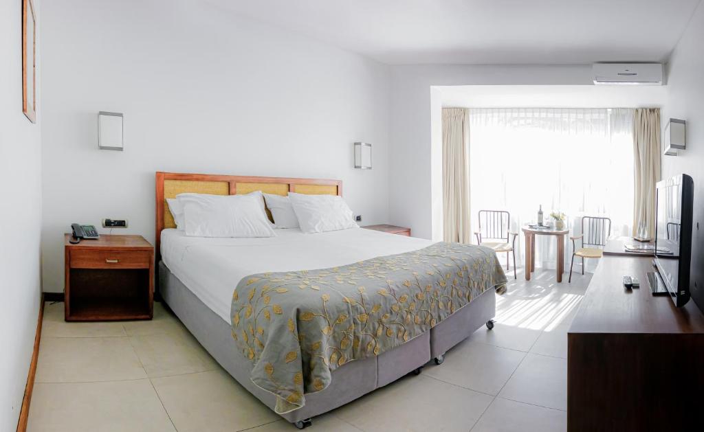 a bedroom with a bed and a table and a window at Hotel Boutique Raíces in Curicó