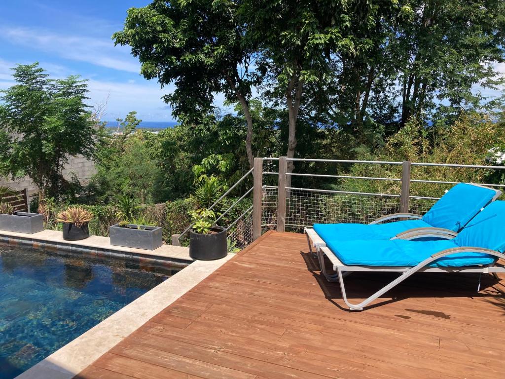 une chaise bleue assise sur une terrasse à côté d'une piscine dans l'établissement Villa Calme et Vue au RDV/Piscine/Plage 10 min, à L'Étang-Salé
