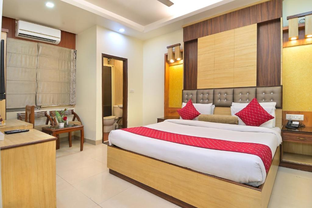 um quarto com uma cama grande e almofadas vermelhas em The Aster Karol Bagh Homely Atmosphere em Nova Deli