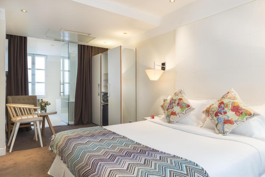 ein Hotelzimmer mit einem großen Bett und einem Stuhl in der Unterkunft Hotel Le Placide Saint-Germain Des Prés in Paris
