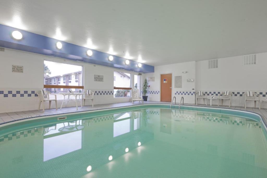 a large swimming pool in a building with chairs at AmericInn by Wyndham Davenport in Davenport