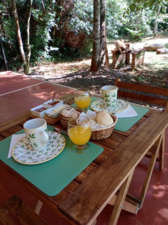 a wooden table with plates of food and glasses of orange juice at Yurtas Ivirareta Glamping in Garupá