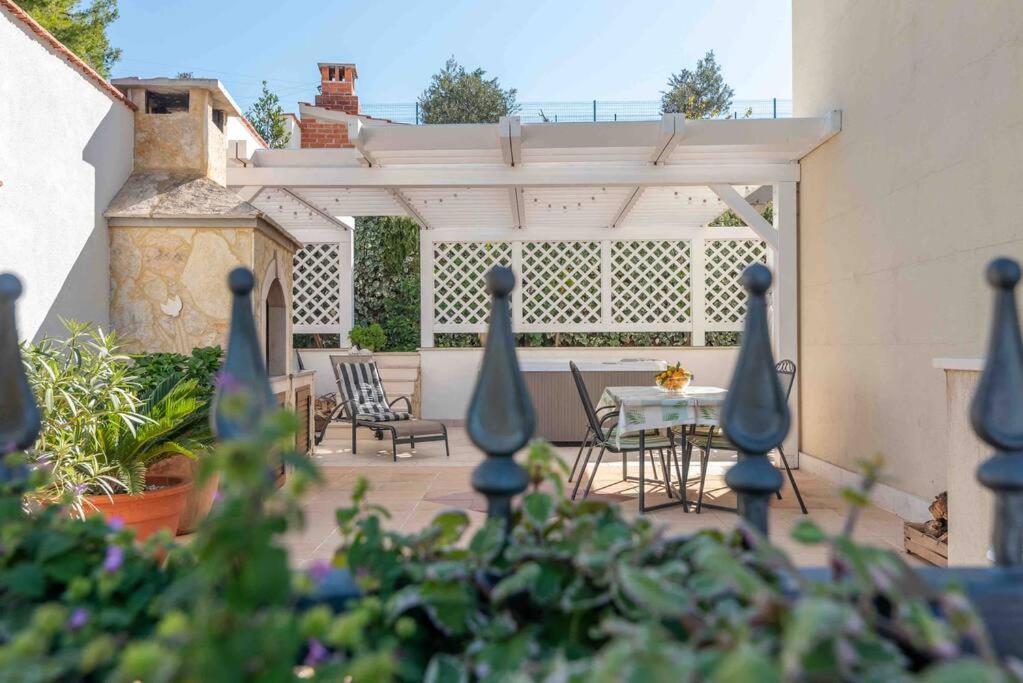 a patio with a table and chairs and a fence at Cozy House in Seget Vranjica