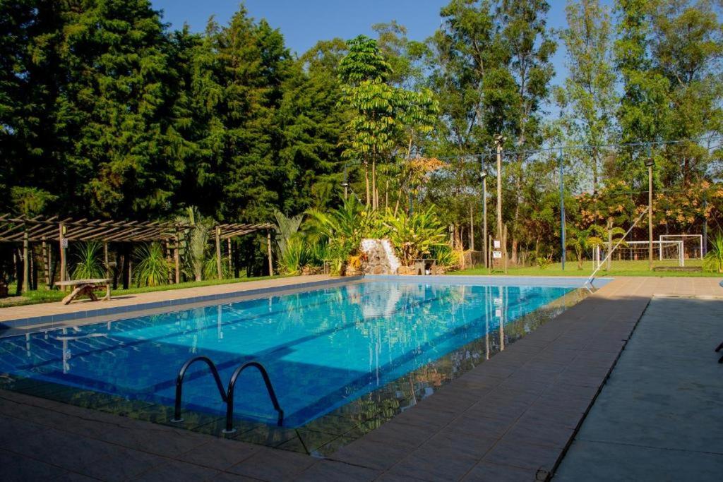 a swimming pool with blue water in a park at Pousada DuBaldo in Holambra