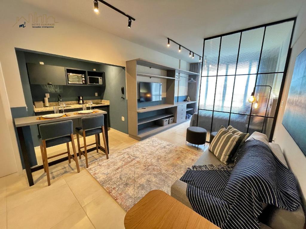 ein Wohnzimmer mit einem Sofa und einer Küche in der Unterkunft Home Time Studios in Florianópolis