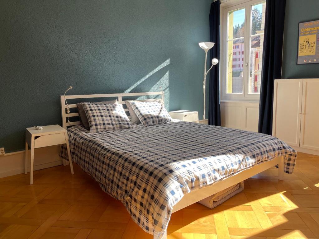 een slaapkamer met een bed met een geruite deken bij Le Locle : bel appartement chaleureux in Le Locle