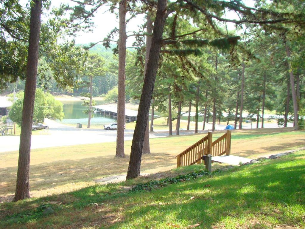 un banco de madera sentado en un parque con árboles en Mountain Harbor Queen Guest Room on Lake Ouachita, en Mount Ida