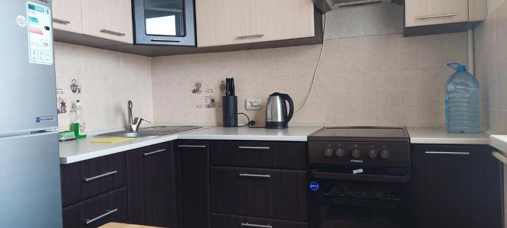 cocina con armarios negros y horno con fogones en Проспект Центральный 6-я слободская, en Mykolaiv