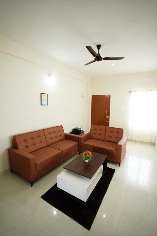 a living room with two brown couches and a ceiling fan at Castle Suites by Haven Homes, Kempegowda International Airport road in Bangalore