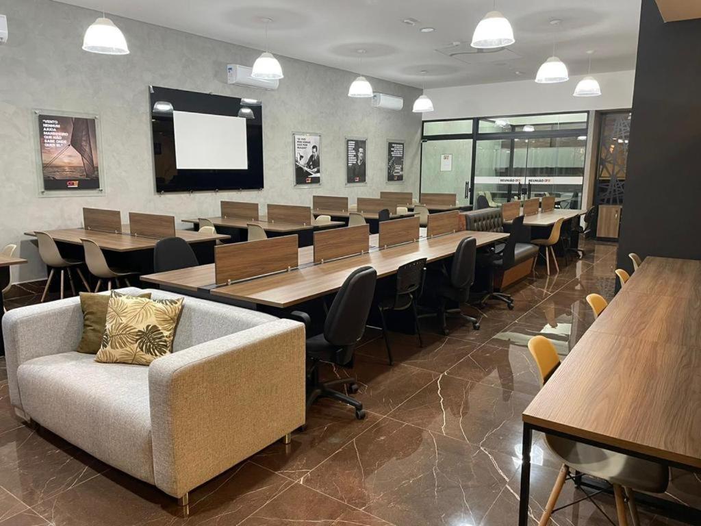 - une salle de conférence avec des tables, des chaises et un canapé dans l'établissement Flat Aconchegante, à Sorocaba