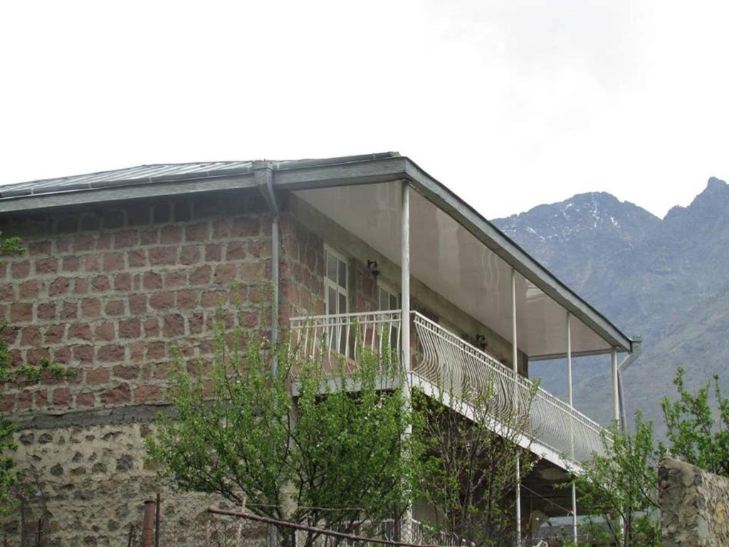 a brick building with a balcony with mountains in the background at Red Stone Guest House in Stepantsminda