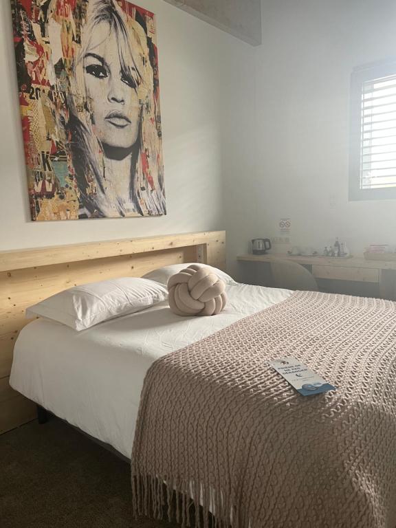 a bedroom with a bed with a painting on the wall at Le B Complexe Hôtel in Lozanne