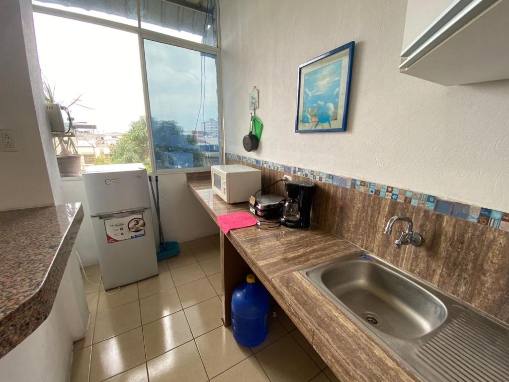 a kitchen with a sink and a refrigerator at Playa Aparts & Suites Malecon in Manta