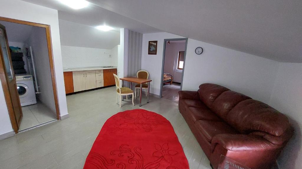 een woonkamer met een leren bank en een rood tapijt bij Apartament MeliMe in Roman