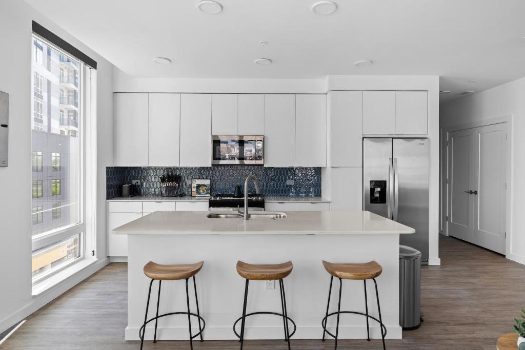 a kitchen with white cabinets and a kitchen island with stools at Locale The Gulch - Nashville in Nashville