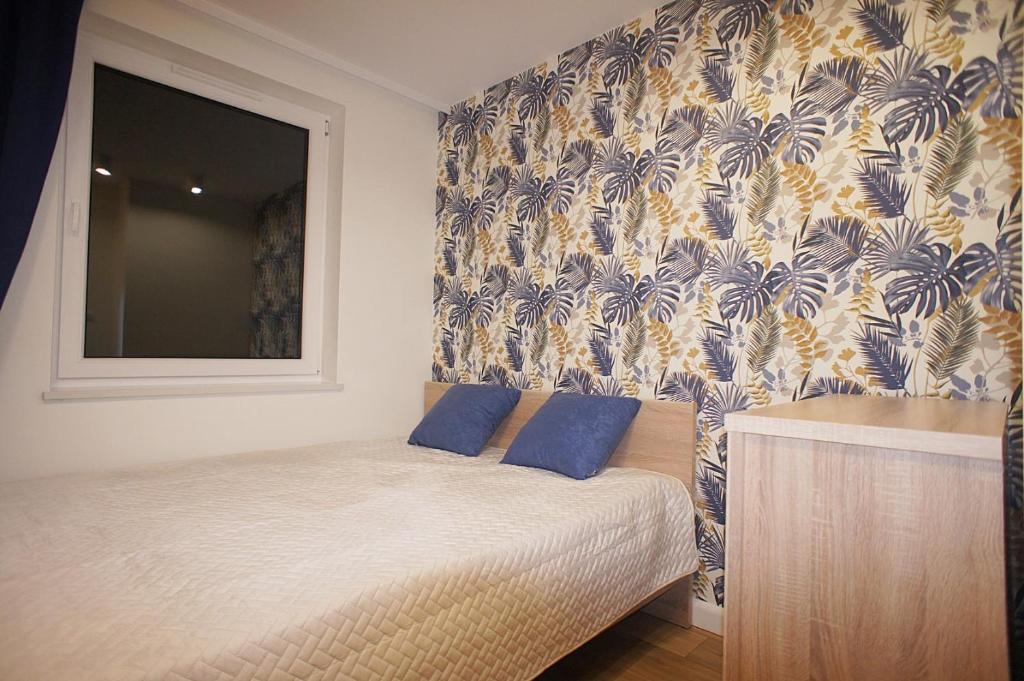 um quarto com uma cama com almofadas azuis e um papel de parede em Drzewna Apartamenty -Augustowska em Zielona Góra