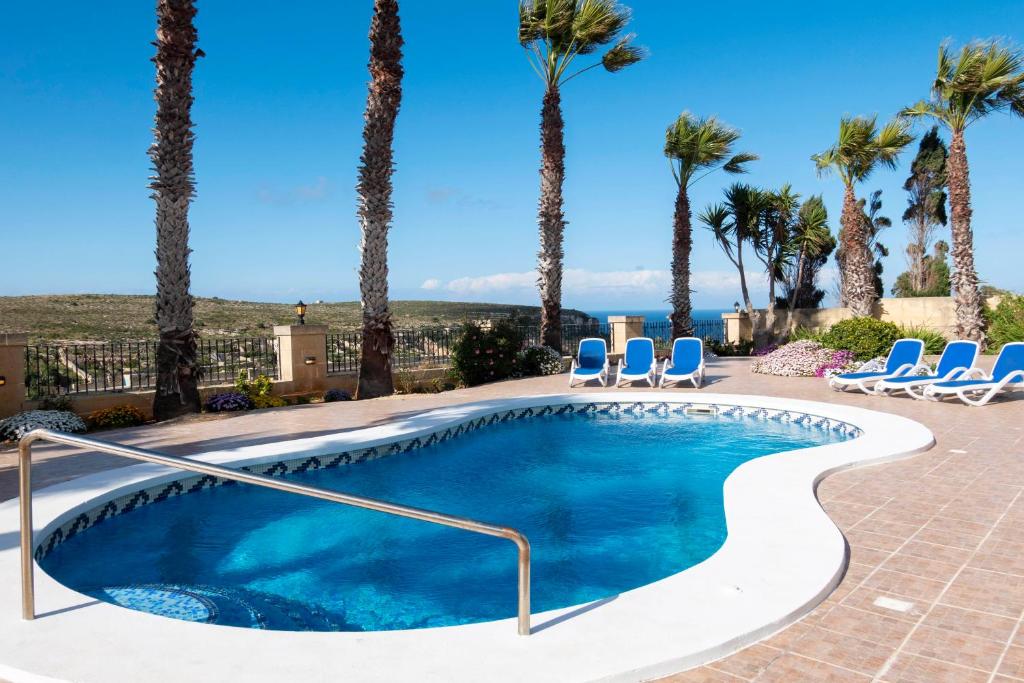een zwembad met stoelen en palmbomen bij Zest Holiday Home in Qala