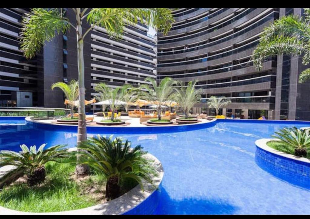 a swimming pool with palm trees and a large building at Fortaleza Landscape Beira-mar: espaço inteiro in Fortaleza