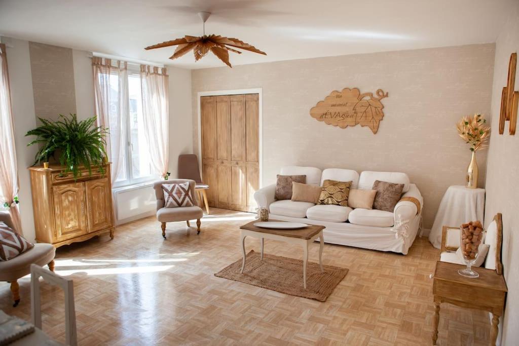 ein Wohnzimmer mit einem weißen Sofa und einem Tisch in der Unterkunft Appartement Un moment d’ÉVAsion in Épernay