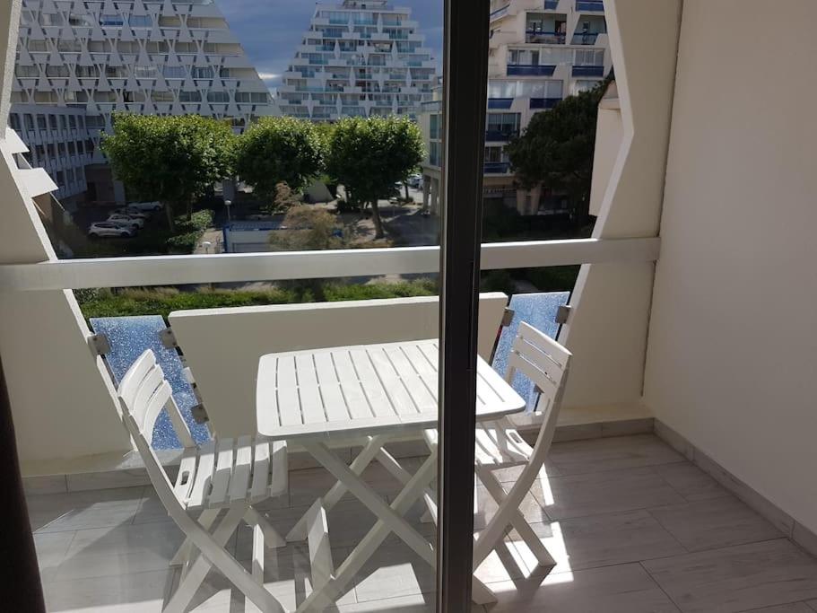 a white table and chairs on a balcony with a window at Studio La Grande Motte, au plus près des plages in La Grande Motte