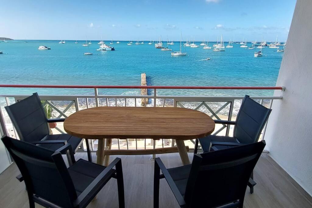 a table and chairs on a balcony with a view of the water at Duplex moderne vue mer des caraibes in Marigot