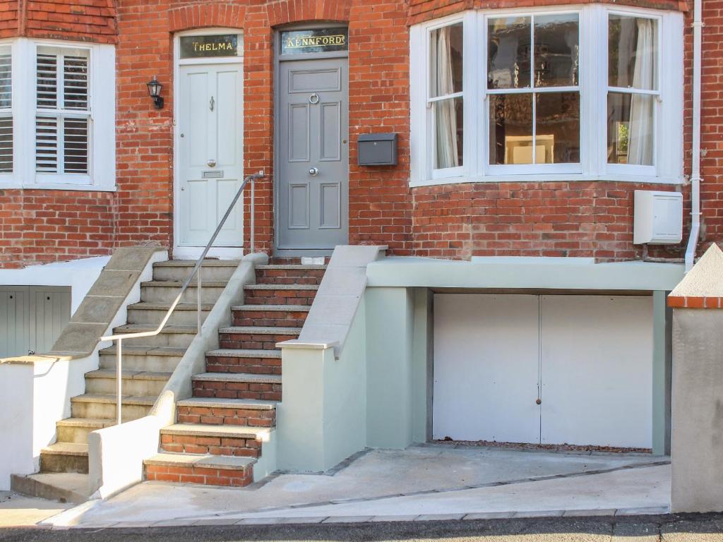 - un bâtiment en briques avec deux portes blanches et des escaliers dans l'établissement Kennford, à Salcombe