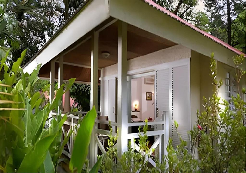 una casa blanca con porche y algunas plantas en EVASION Bungalow Tropical Spa, en Sarraméa