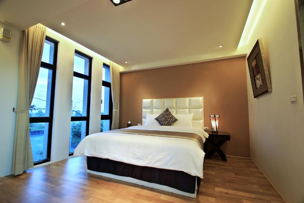 a bedroom with a large bed and large windows at Han-Shian Boutique B&amp;B in Dongshan
