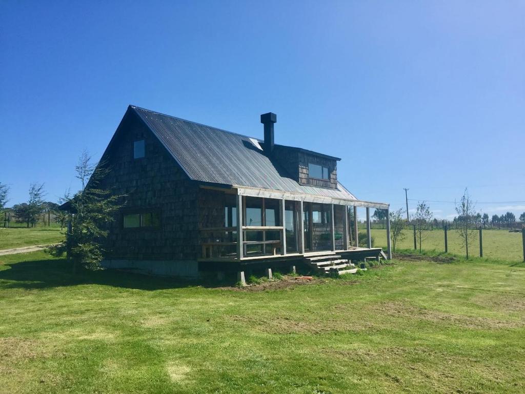 una gran casa de madera en un campo de hierba en Cabaña con chimenea en Pto Varas, en Puerto Varas