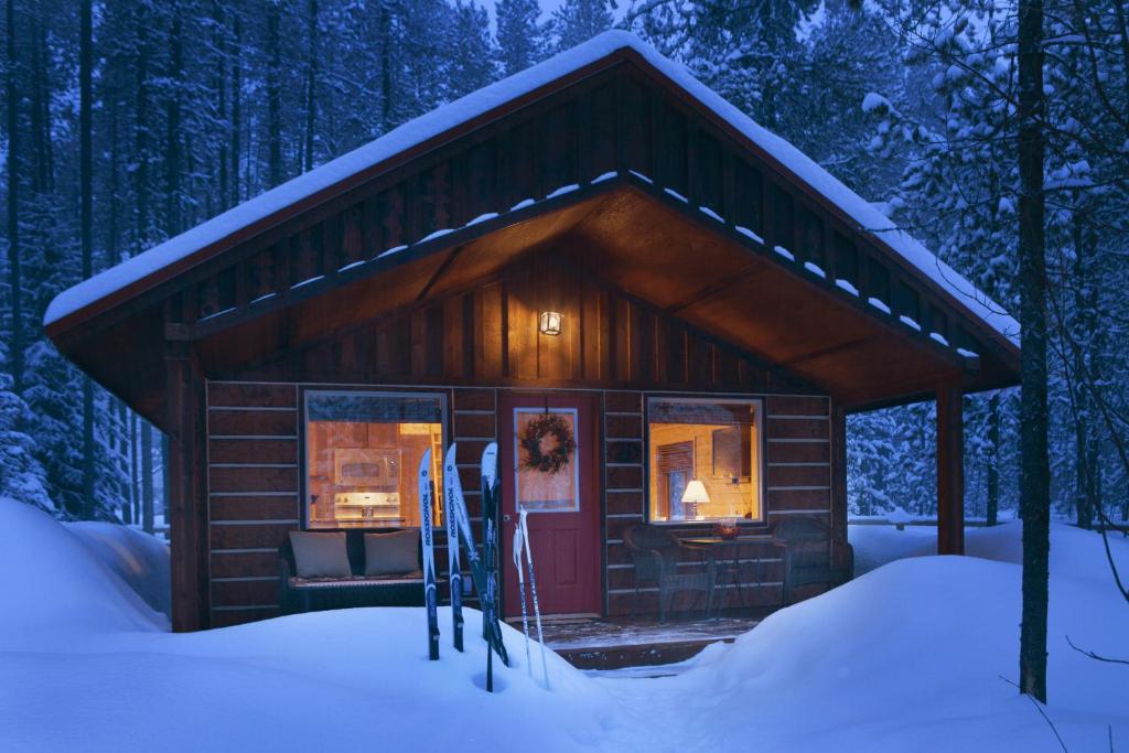 a cabin in the snow with skis in front of it at Reclusive Moose Cabins in West Glacier