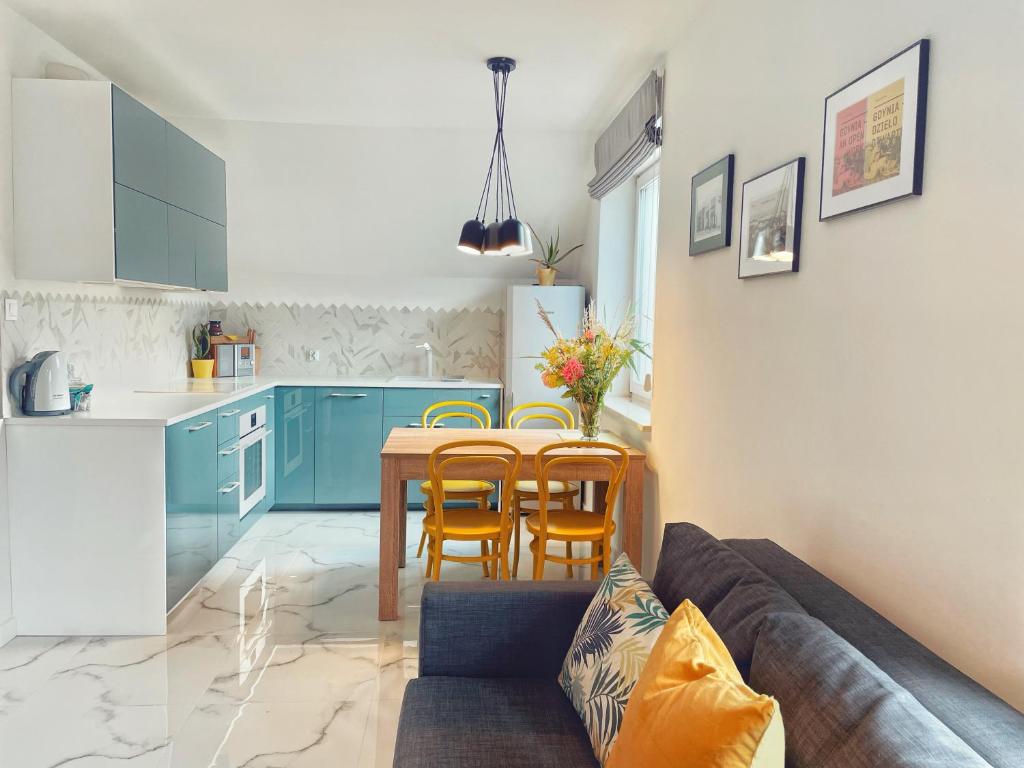 a kitchen with blue cabinets and a table and chairs at Urban Jungle - luksusowy apartment w Gdyni. in Gdynia