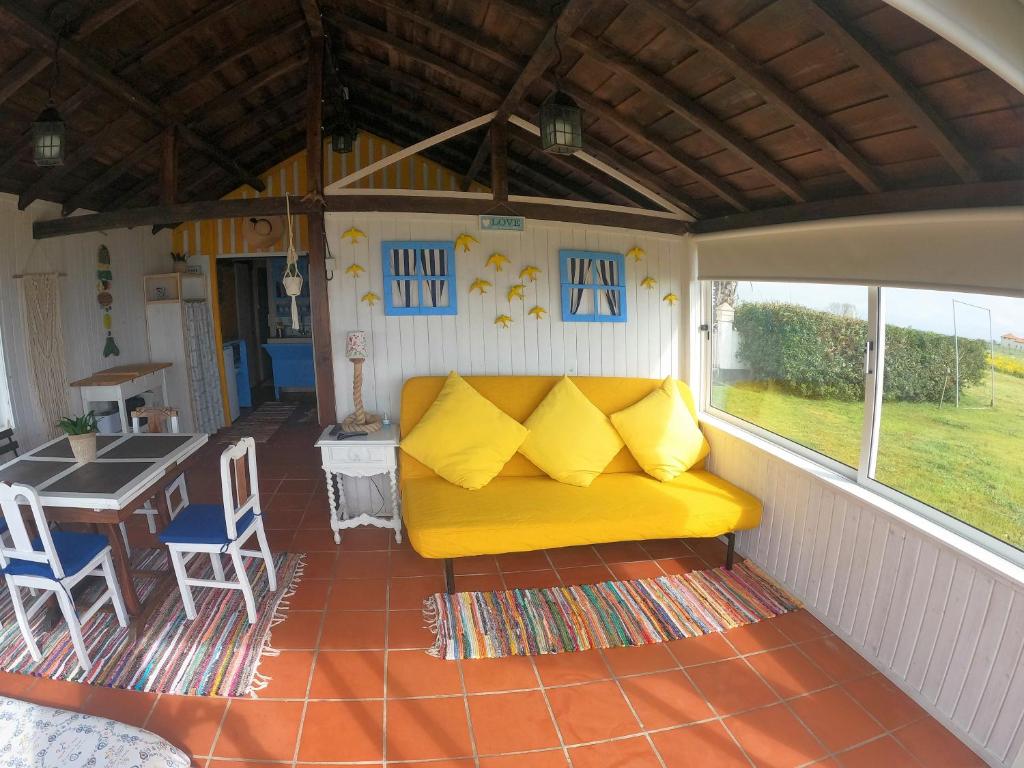 um sofá amarelo num alpendre coberto com uma mesa em Casa dos Flamingos em Murtosa
