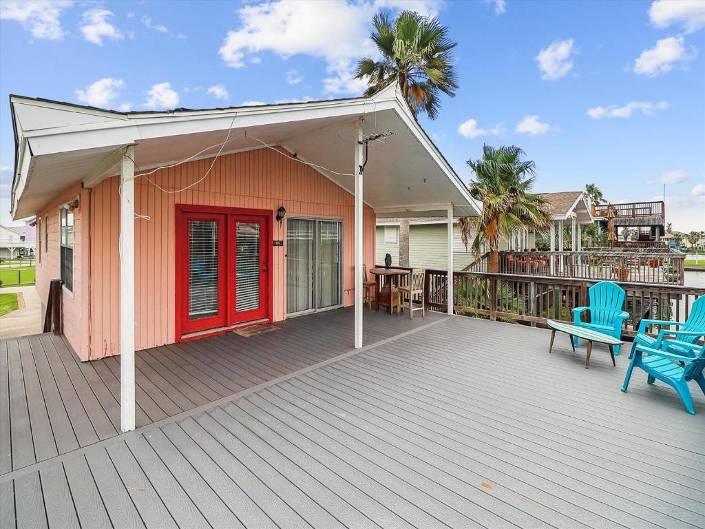 a deck with a red door and two blue chairs at Peggys Hideaway in Galveston