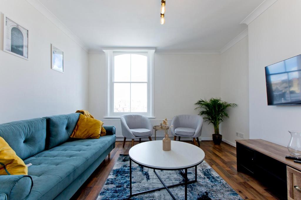 a living room with a blue couch and a table at Marvelous Flat in Earls Court - London in London