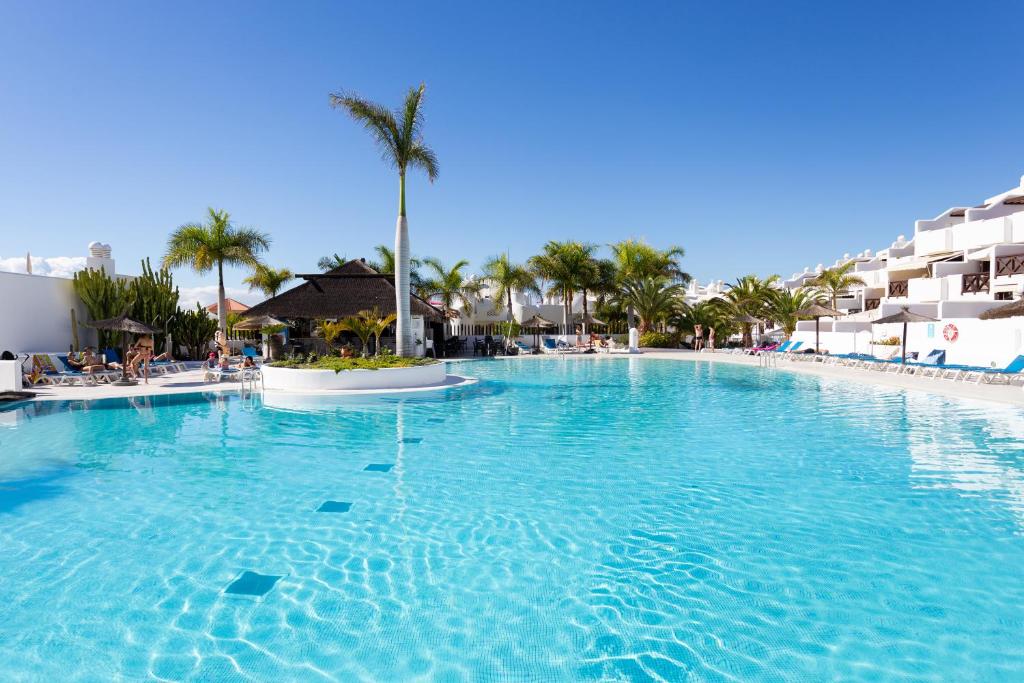 uma grande piscina num resort com palmeiras em apartamento paradise luxury em Playa Paraiso