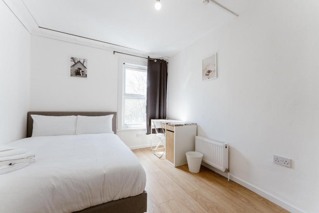 a white bedroom with a large bed and a desk at Mile End Double Rooms 27 Guest house in London