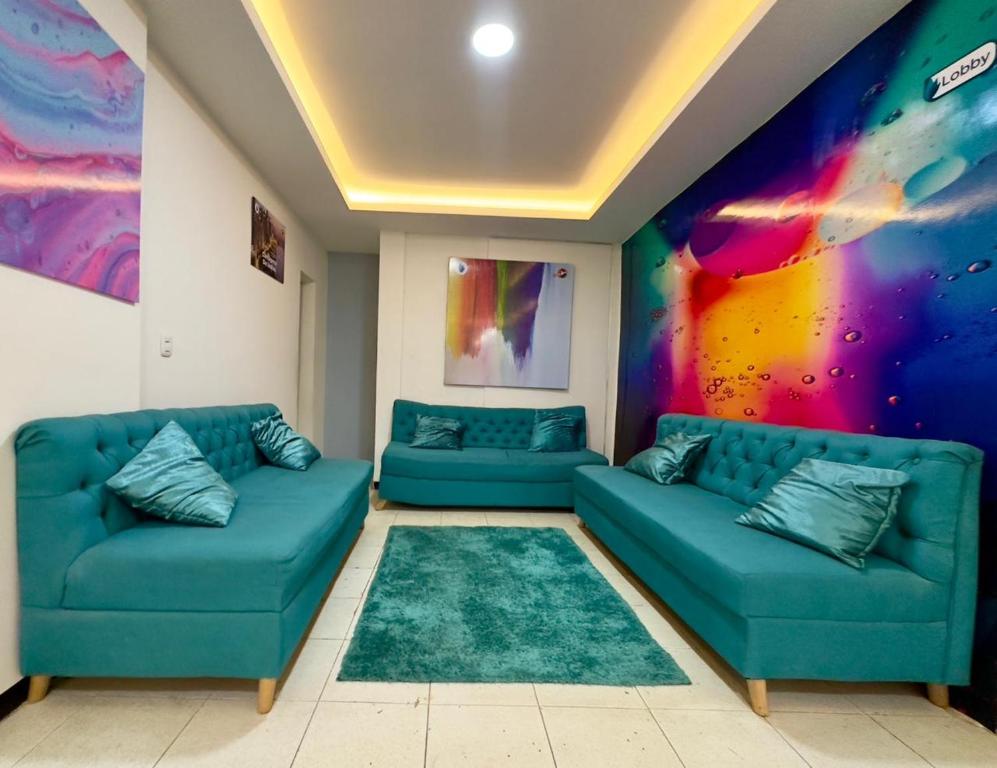 a living room with two blue couches and a colorful wall at Hotel Santo Tomas Bogota in Bogotá