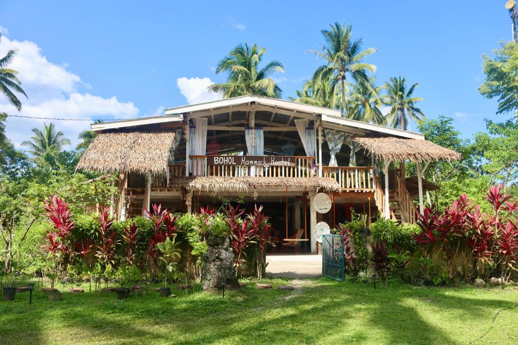 a house with a porch and a grass roof at Bohol Hammock Hostel in Batuan