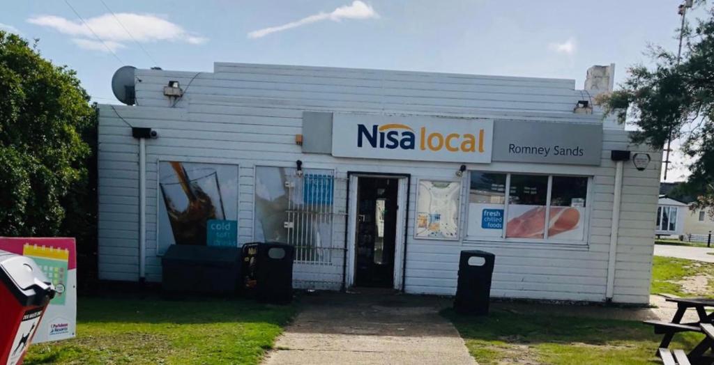 a nsa local pharmacy building with a sign on it at Cosy holiday home at Romney Sands in New Romney