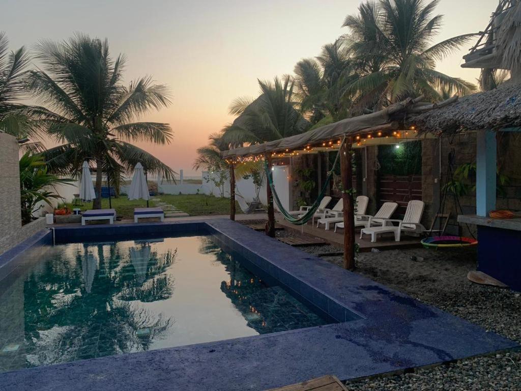 a swimming pool next to a house with palm trees at Casa Playa linda 28 in El Desengaño