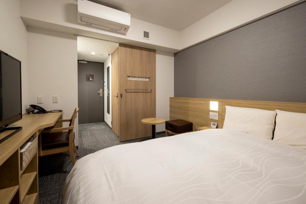 Postel nebo postele na pokoji v ubytování Dormy Inn Hiroshima Annex