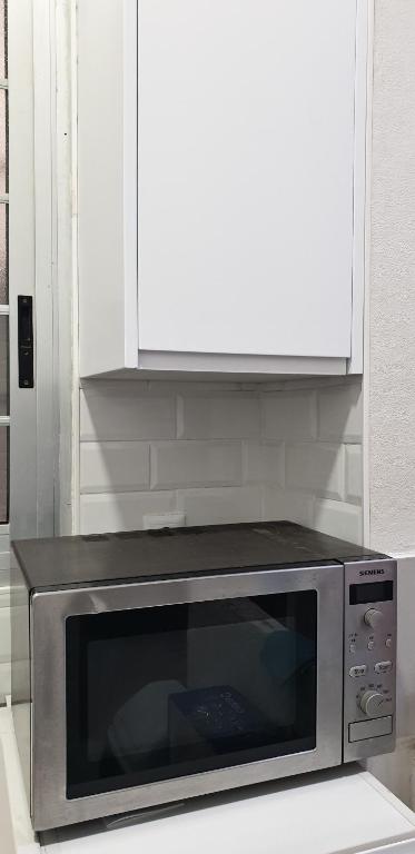 un horno de microondas con un armario encima en la cocina en Habitacion en casa de familia "ValenciaBonita", en Valencia