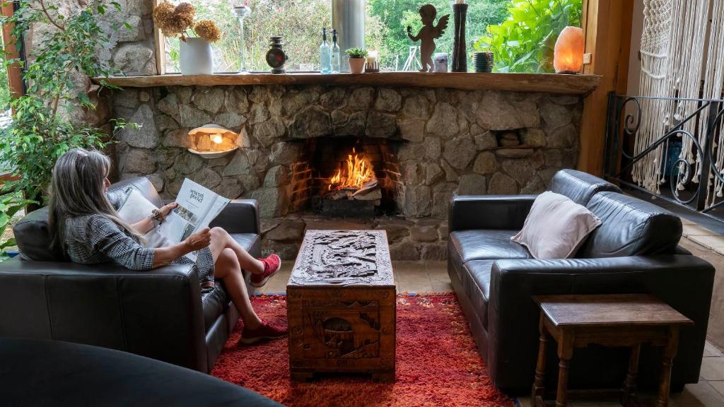 a woman sitting on a couch in a living room with a fireplace at Dreamers in Mount Beauty