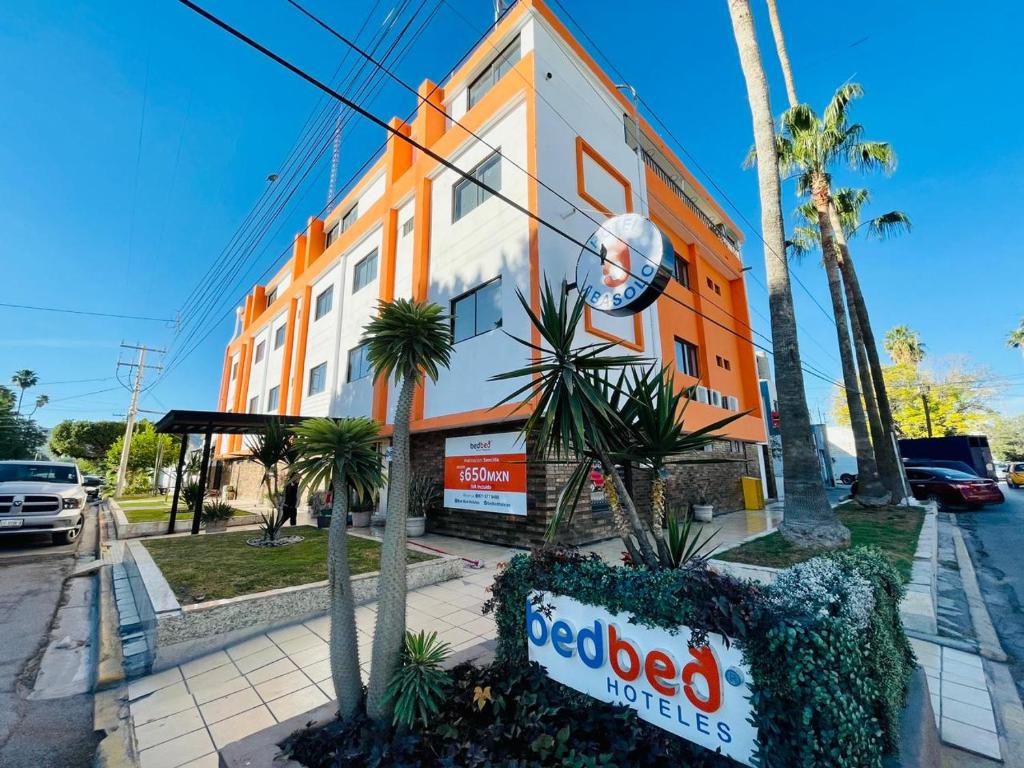 un edificio naranja y blanco con un letrero de la rededia delante de él en Bed Bed Hotel Abasolo en Torreón