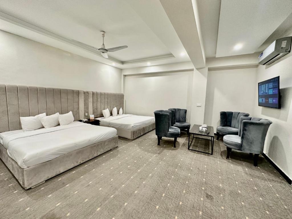 a hotel room with two beds and chairs at MUDAN hotel and suite in Islamabad