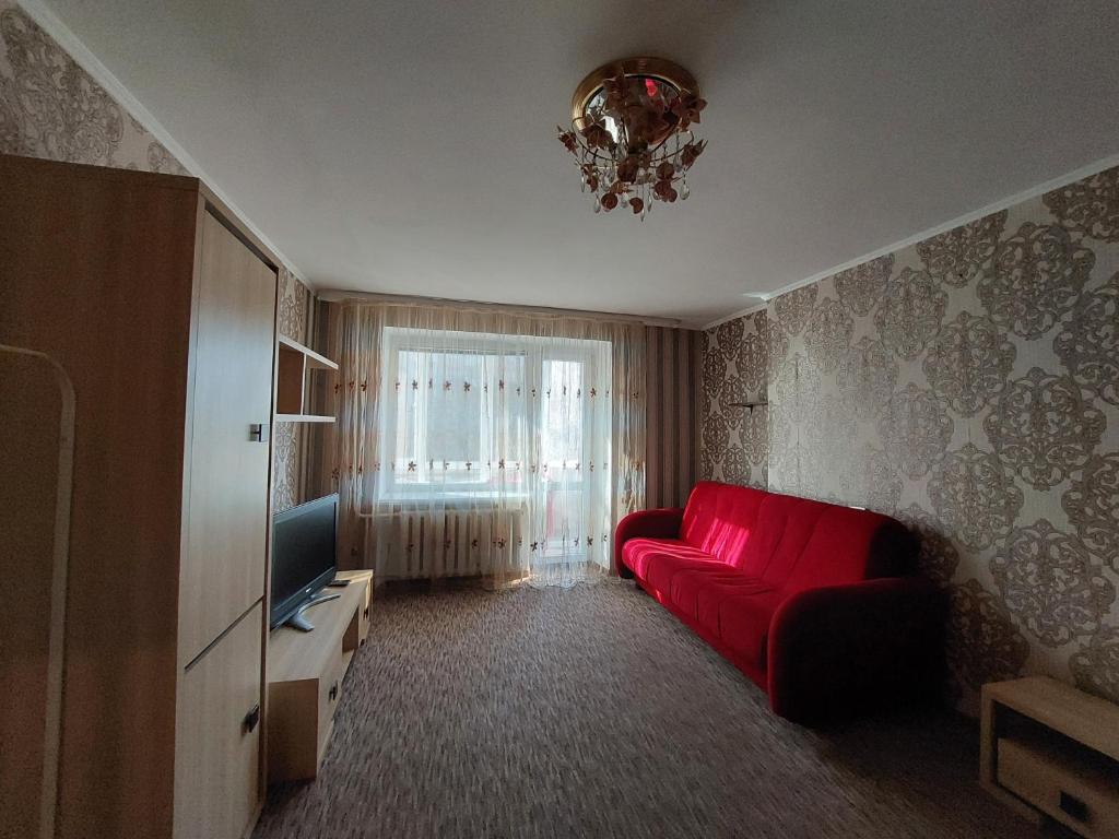 een woonkamer met een rode bank en een televisie bij Однокімнатна на проспекті Соборності, біля Там-таму in Loetsk