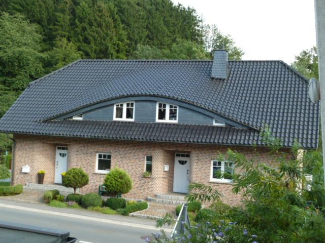 ein großes Backsteinhaus mit schwarzem Dach in der Unterkunft Ferienwohnung Lindlar in Lindlar